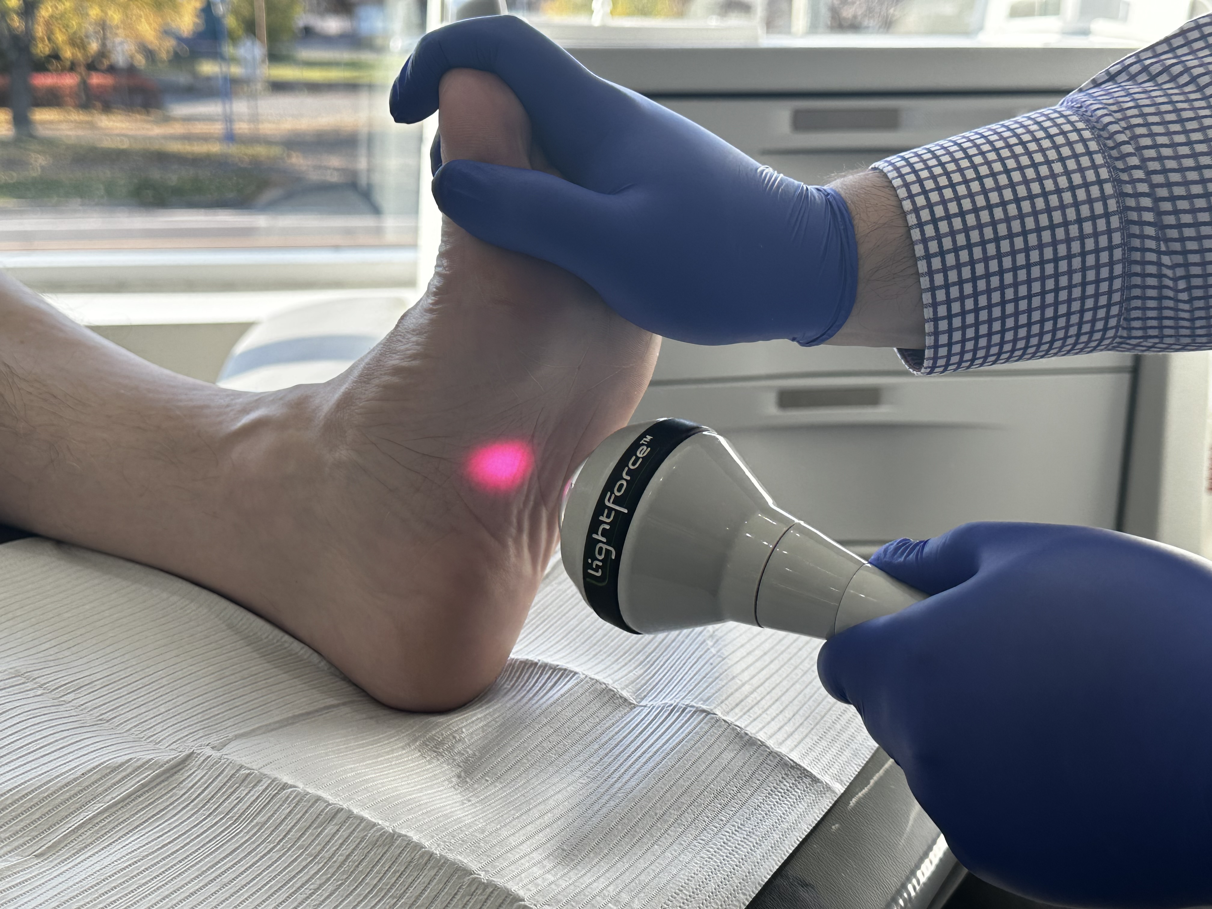 Application de laser au niveau de l'arche du pied sur un patient