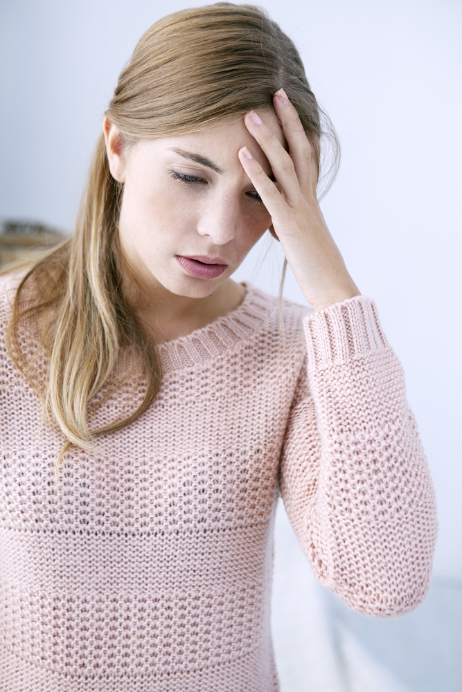 Jeune femme qui se tient la tête car elle a mal à la tête