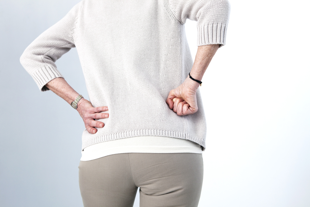 Femme qui se tient debout de dos et qui a les mains sur ses flancs